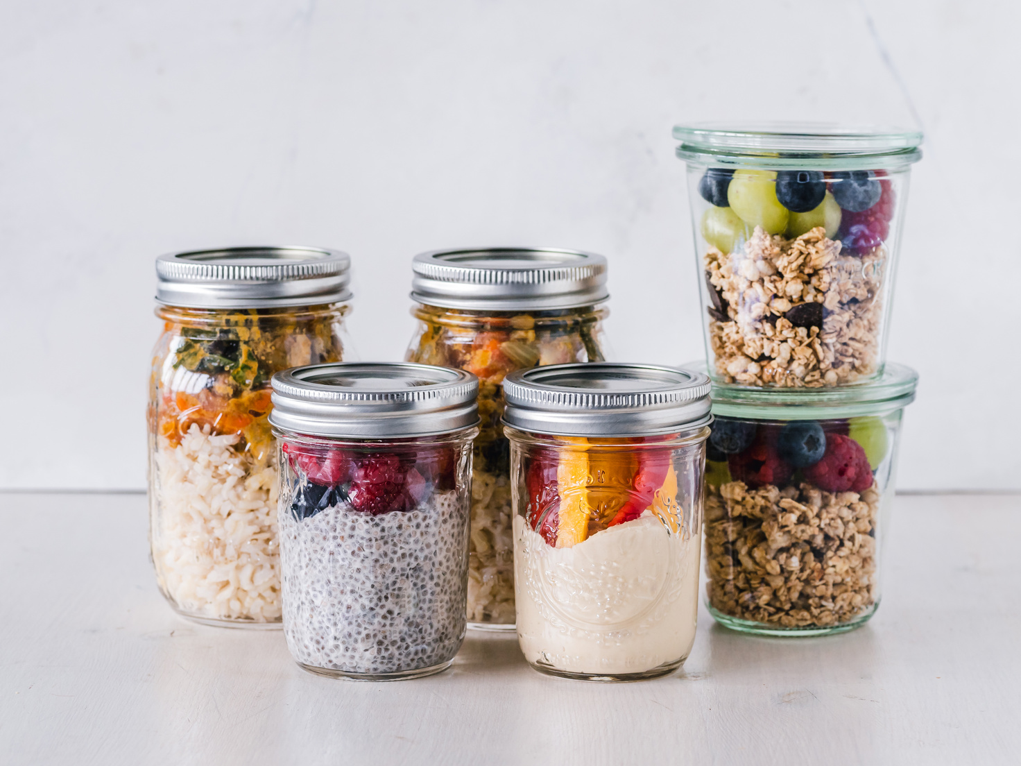 Six Fruit Cereals in Clear Glass Mason Jars on White Surface